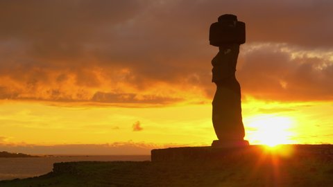 SILHOUETTE, LENS FLARE, COPY SPACE: Dark clouds gather above the historic moai statue by the scenic shore of Easter Island. Idyllic shot of sunset illuminating the ocean behind the fascinating moai