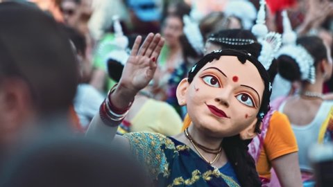 Kyiv, Ukraine - 6 June, 2019: Happy miscellaneous religious people in traditional costumes dancing at the Krishna carnival in the city. Portrait of beautiful indian woman wearing mask at the festival