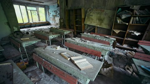 Wide-angle view of abandoned old dirty classroom with radioactive furniture in Prypiat town. View inside scary empty school left instantly after the Chernobyl disaster.