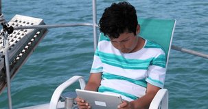 Portrait of a preteen schoolboy with digital tablet computer on boat deck at summer holiday