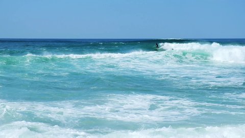 Surfer rides giant blue ocean wave. Big wave surfing. Slow motion video