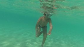 Closeup underwater view of cute funny kid swimming in blue sea water during summer vacations at beach of resort. 