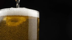 Beer is pouring and foaming in Glass on black background closeup