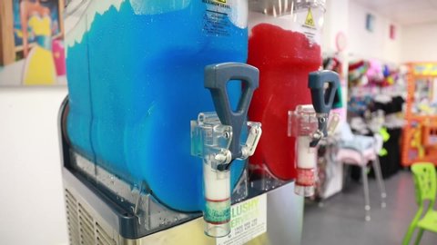 Slushy machine with glass top blending blue and red liquids