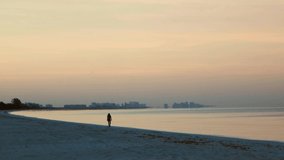 A female walking along Bonita Beach, FL early one morning just after sunrise.