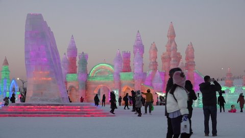 HARBIN, CHINA – JANUARY 2019: People visit spectacular ice sculptures decorated with neon lights at Harbin ice festival - China Winter nightlife scenes