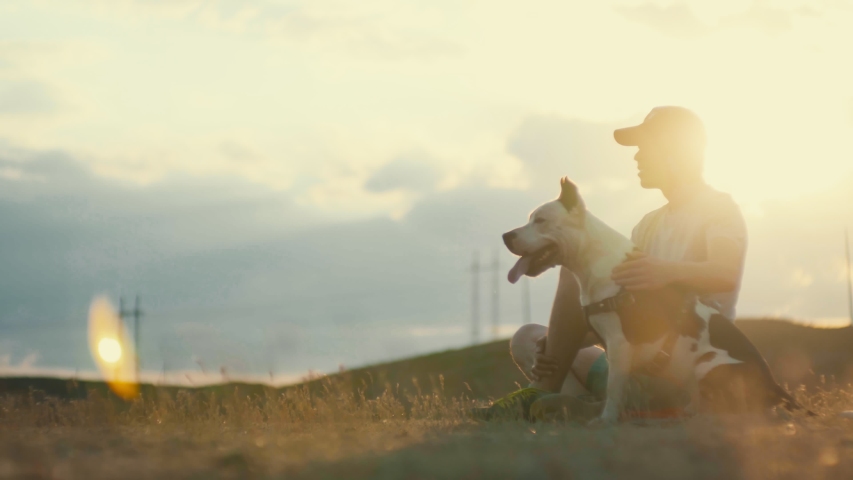 After a long day of training the owner sits with his dog in a field