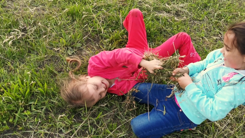 two little girls sitting on grass: стоковое видео (без лицензионных платеже...