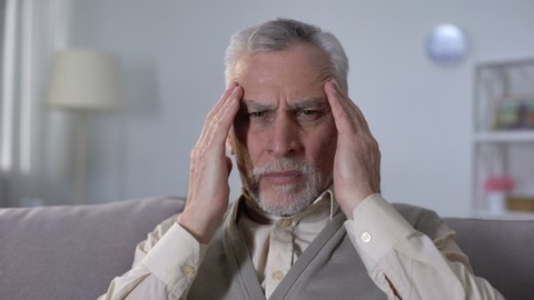 Old man suffering migraine, symptom of ischemic stroke, neurological problems
