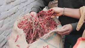 slow motion clip of a buyer and vendor examining dried red chilies at old delhi in india- 180p