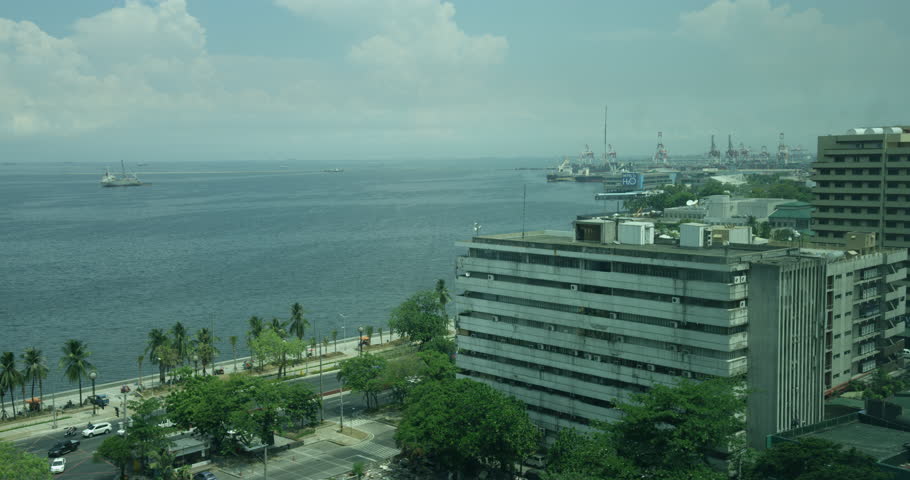 Manila - MAY 2015: Busy streets near Mall of Asia Philippines. Run down hotel building overlooking the Philippines Manila Bay
