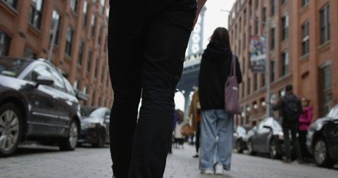 Close Up of Person Walking Through The Streets Of New York City Towards the Iconic Manhattan Bridge in The Trendy Dumbo Brooklyn With Tourists Enjoying and Experiencing The City.