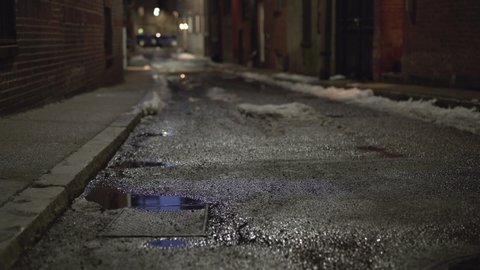 Dark side street of large city with puddle of water 4k