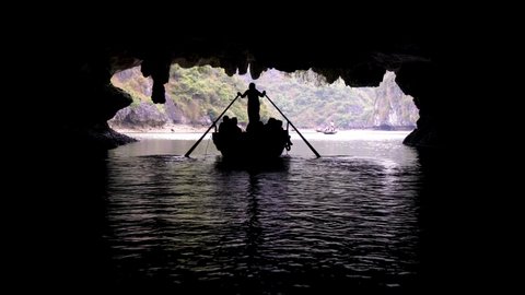 Tourists in traditional local boats being guided through the caves of the limestone islands of Ha Long Bay, Cat Ba National Park, Vietnam
