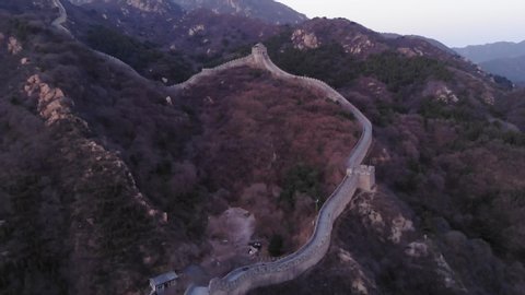 Great Wall of China climb up by mountain slope, aerial shot at dusk. North part of Badaling section, light stone fortification on dark mountainside