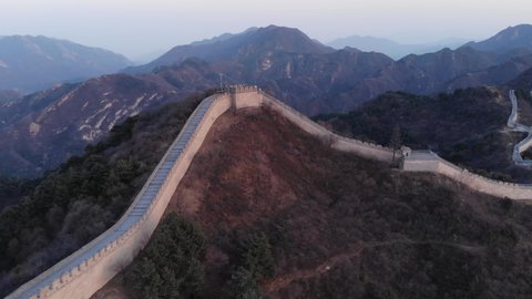 Great Wall of China at evening twilight, aerial shot at Badaling site. Tower topping hill, embattled structure follow slopes on right and left. Highland area of Yanqing District