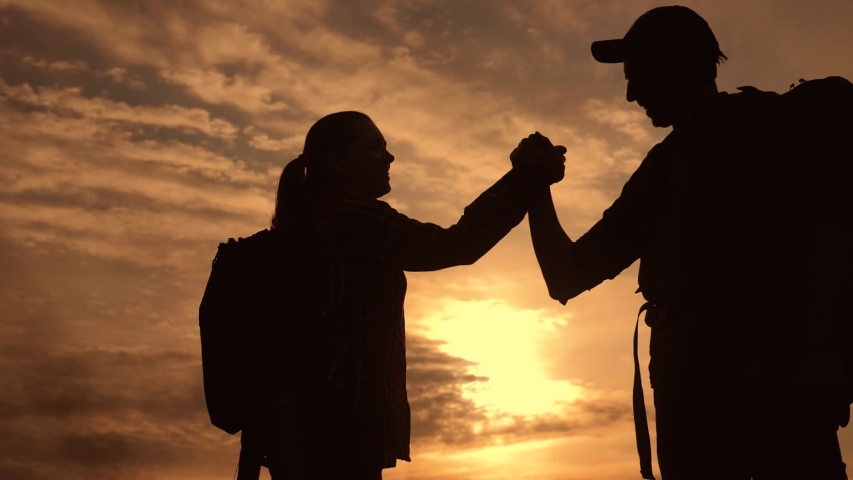 Teamwork business journey concept win. team tourists man and woman sunset silhouette help shake hands victory success. slow motion video. tourism husband and wife on top of the mountain lifestyle have | Shutterstock HD Video #1032243179