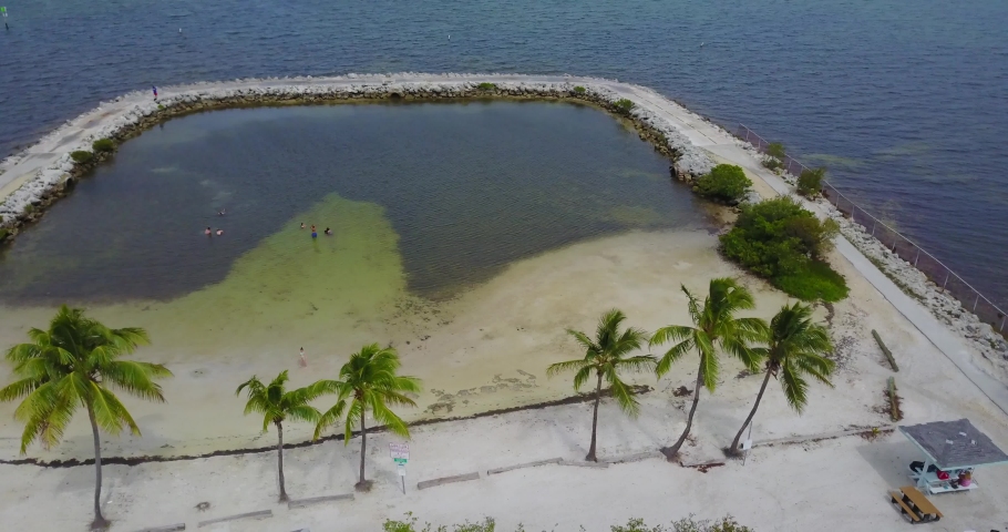 AERIAL: starting behind some palm trees then moving towards the center of a closed off beach area in Key Largo, Florida.