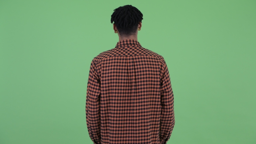 Rear view of young African man with dreadlocks thinking and looking around
