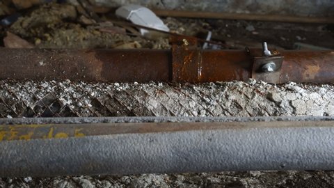 Iron rusty pipes leaking in basement of old house water drops splashing on pipe repair clamp dolly shot.