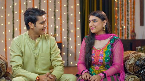 Young Indians siblings showing love and care - brother-sister relationship - Raksha Bandhan concept. Good looking adults in traditional wear. Cute brother teasing and giving gift to his sister