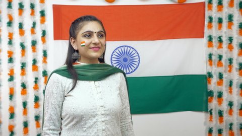 Young Indian girl looking up in the sky and saluting Indian tricolor flag - celebrating Independence Day. Beautiful woman in a white kurta and tiranga dupatta saluting Indian armed forces - Patriotism