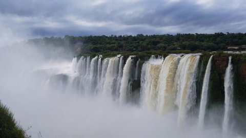 The beautiful Iguazu Falls on the border of Brazil and Argentina from the Argentina side on a cloudy day with mist from the falls rising.