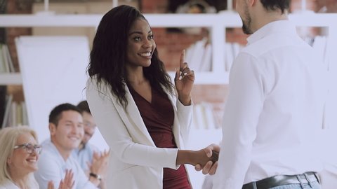 Smiling black female employee get rewarded handshake caucasian boss, helpful manager shake hand of successful african business woman congratulate promote, appreciation recognition at work concept