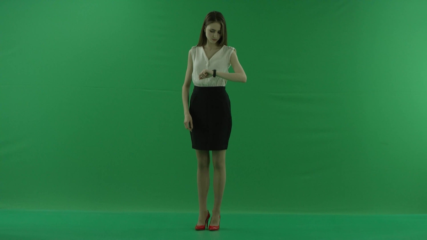 a thoughtful woman is waiting and loking at her whatch . She wears formal dress: white shirt and blak skirt. Businesswoman think, got idea over green screen