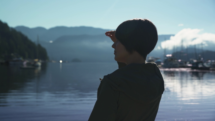 Woman silhouetted as she looks out at a marina in British Columbia, Canada.