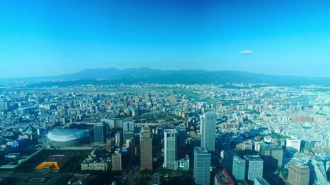 A very high aerial time lapse of Taipei City, Taiwan on a hazy day. The view looks out over the city to the mountains and horizon off in the distance.