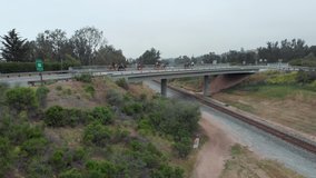 Aerial footage of group of horses passing overpass overlooking train tracks and freeway