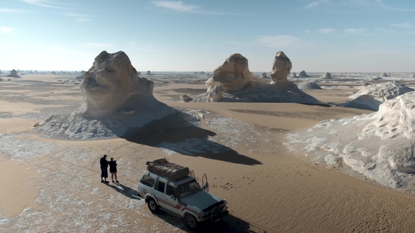 The White Desert & Black Desert in Egypt. Two people standing next to a 4 wheel drive in the desert