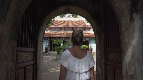 Blonde Girl walking towards a Buddhist temple and statue at Marble Mountains in Da Nang, Vietnam