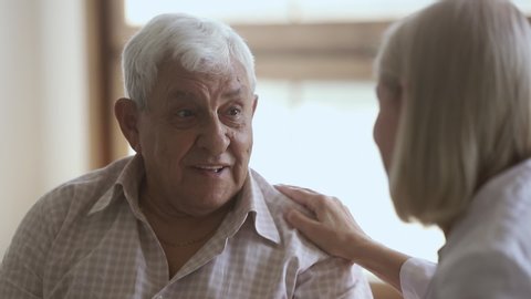 Elder old man talking to mature doctor caregiver telling complaints laughing, female nurse listening supporting senior patient having trust conversation giving care helping providing medical services