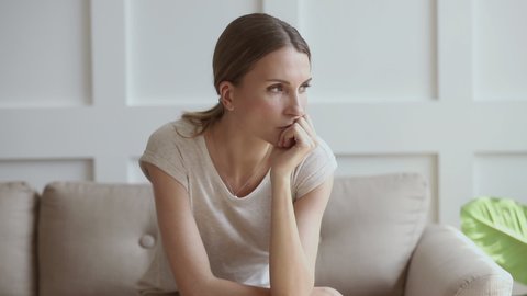 Worried insecure young lady thinking of problem sitting alone at home thoughtful depressed woman feeling concerned doubtful making difficult decision troubled with anxiety, doubt or unwanted pregnancy