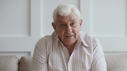 Happy senior elder man looking talking to camera recording vlog or making call at home, old grey-haired aged grandfather doing video chat or shooting footage for channel, webcam view