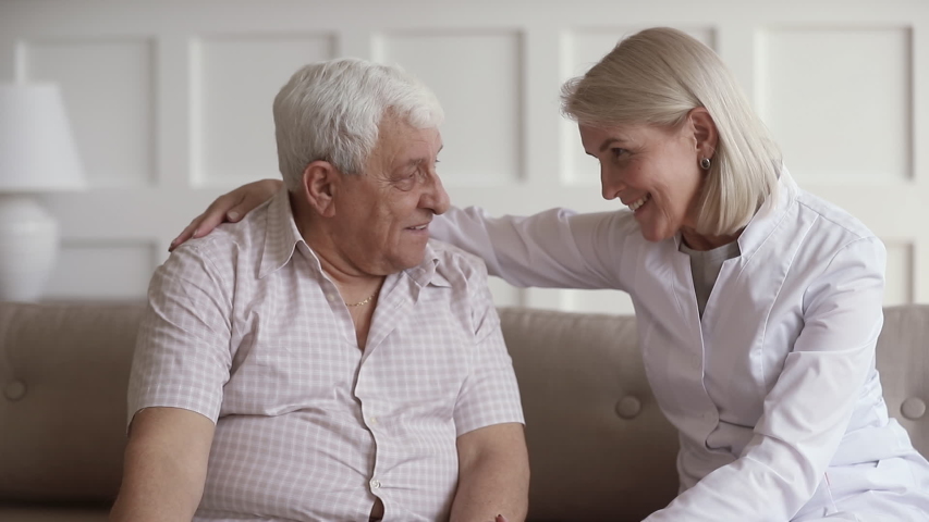 Middle aged woman nurse doctor caregiver in medical uniform talking cheering old elder man give empathy support encourage senior patient make laugh help with health problem having trust conversation | Shutterstock HD Video #1032303980