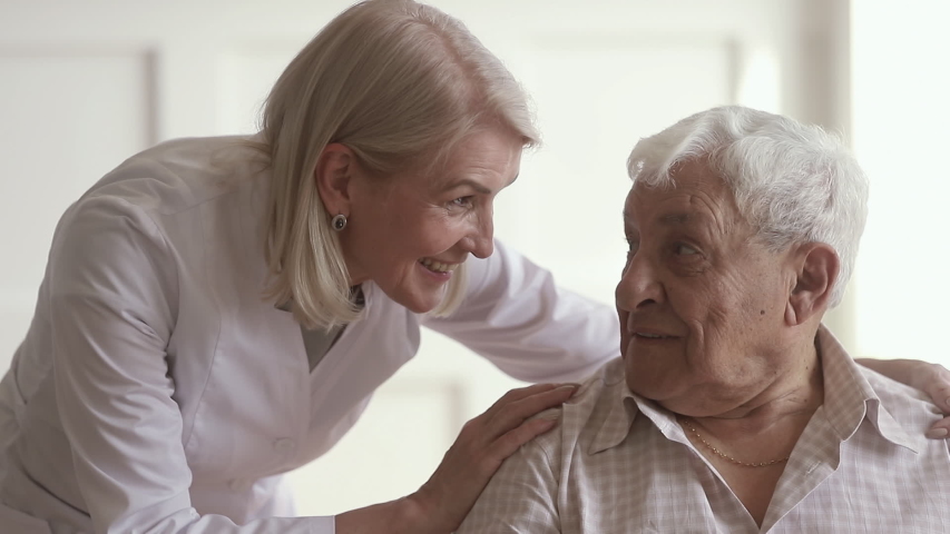 Smiling mature kind woman nurse doctor talking to happy disabled old elder man, happy female therapist cheering taking care of senior patient giving support and medical assistance in retirement house Royalty-Free Stock Footage #1032303983