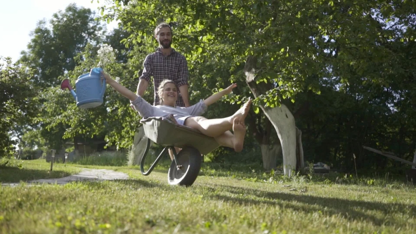 Young happy couple having fun at the backyard and riding a country trolley.