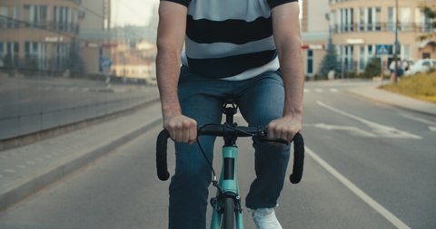 Cyclist guy riding fixed gear sport bike in sunny day on city. Hipster man in casual summer cloths and bicycle on street. Front tracking close-up of wheels. 4K slow motion raw video footage 60 fps 스톡 비디오