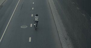 Cyclist guy riding fixed gear sport bike in sunny day on city. Hipster man in casual summer cloths and bicycle on street. Top view tracking Healthy concept. 4K slow motion raw video footage 60 fps