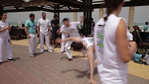 Haifa, Israel - June 8th 2019: Roda (Capoeira circle) at the beach promenade. Fit practicioners of the art playing in the center.