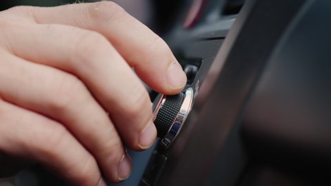 Male hand adjusts the tuning of the car radio