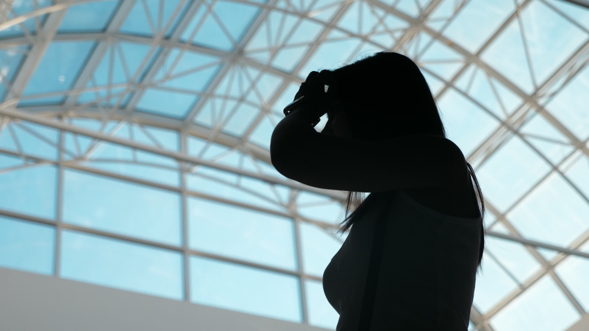 silhouette of young beautiful positive woman waiting for a plane in the airport