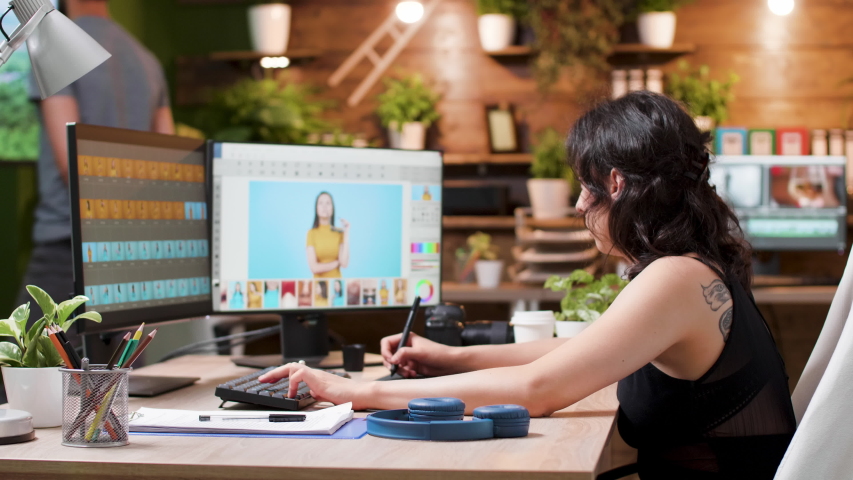 Female photographer edits photos in creative media agency office. In the background - a man is working on other projects on the computer | Shutterstock HD Video #1032326360