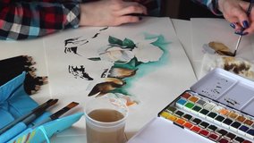 Young girl artist paints beautiful birds with watercolor on paper