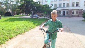 Closeup view of happy white kid learning to riding bike outdoors in green city park. Real time full hd video footage.