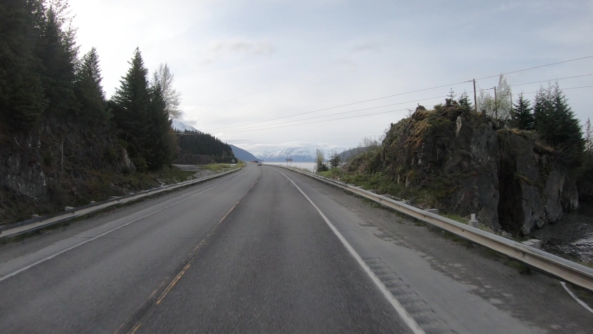 POV; Driving along Turnagain Arm on Seward Highway just south of Anchorage Alaska,road construction signs with Chugach Mountains in Background