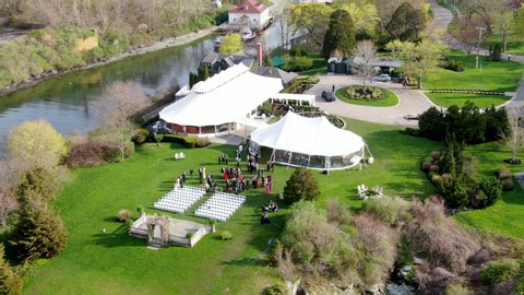 Aerial view of wedding reception ceremony setup with big white tents and people enjoying a drink before ceremony start. Castle Hill Inn, Newport, Rhode Island, USA. 05/13/2019